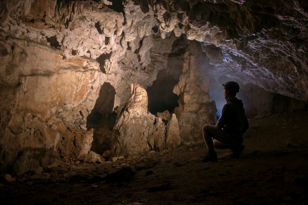 Cave explorer looking at flowstone formations by Cheile Cutler, curated by Adrian Mag on Unsplash
